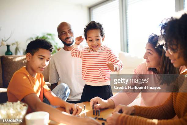 happy multiracial family with three children playing domino at home. - family game stock-fotos und bilder