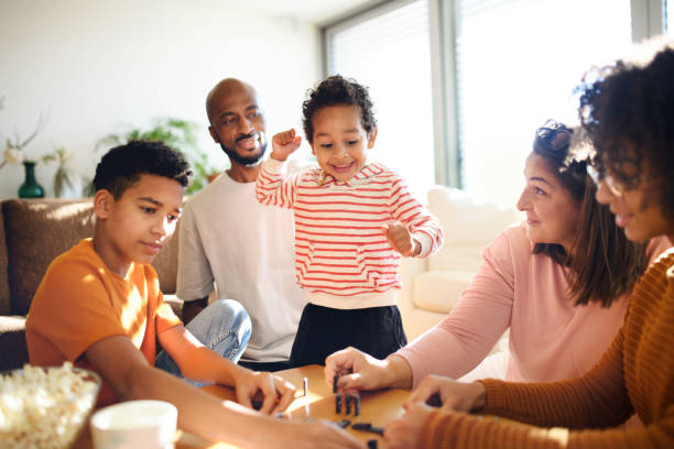 صورة لعائلة مكونة من أب وأم وثلاثة أبناء يقضون وقت مسلي في المنزل