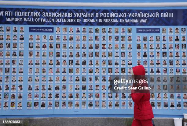 Woman walks past the Wall of Remembrance, which shows the photographs, names and birth and death dates of approximately 4,500 professional and...