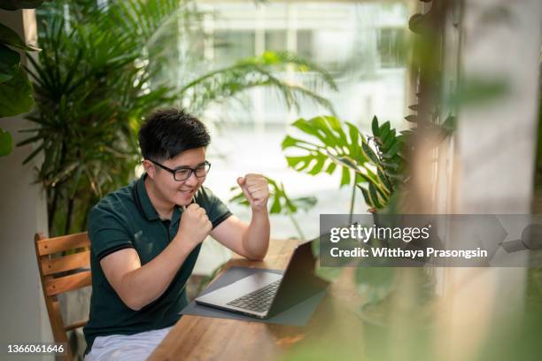 cheerful man celebrating victory online with laptop - bid offer stock pictures, royalty-free photos & images