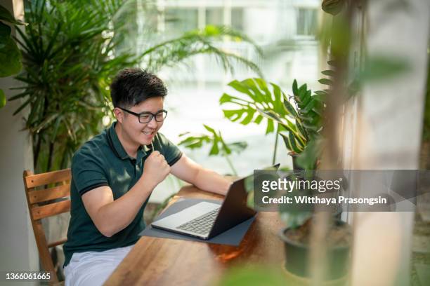 cheerful man celebrating victory online with laptop - home auction stock pictures, royalty-free photos & images