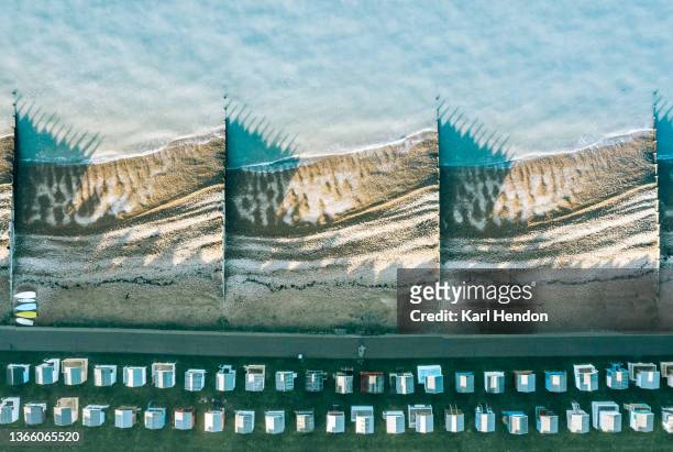 an elevated daytime view of beach huts and beach - groyne photos et images de collection