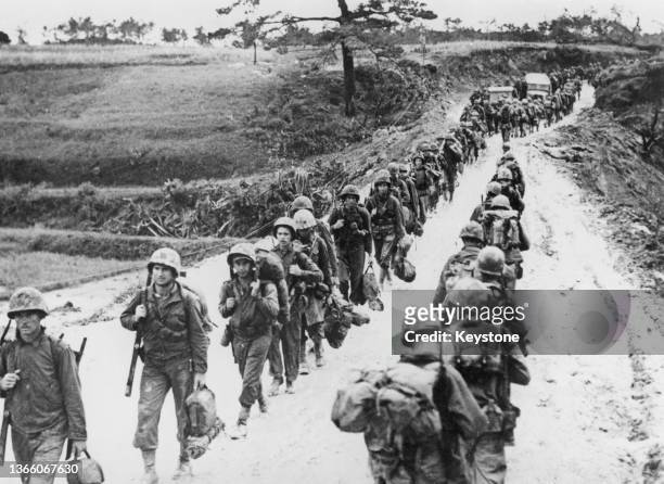 Two columns of 1st and 2nd Marine Division troops from the III Amphibious Corps of the United States Tenth Army pass each other on the march going to...