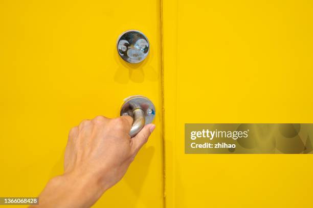 close-up of human hand grabbing handle of yellow door - doorknob stock-fotos und bilder