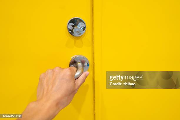 close-up of human hand grabbing handle of yellow door - doorknob foto e immagini stock
