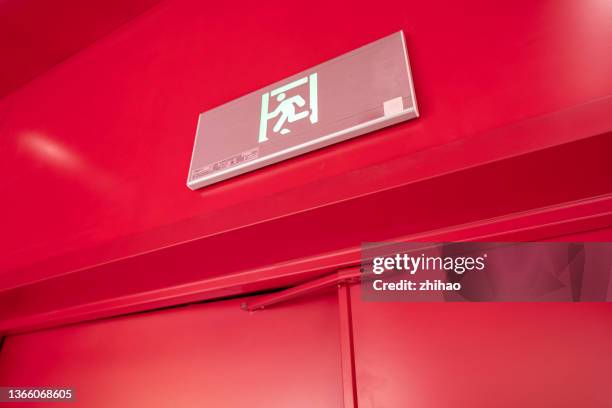 emergency exit sign on red wall fire door - fire door stock pictures, royalty-free photos & images