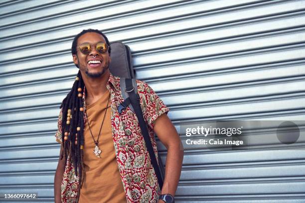 portrait happy male musician with guitar case - caiaimage stock-fotos und bilder