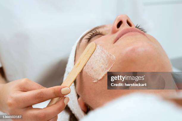 dermatologist applies exfoliating cream to woman's face - exfoliation face stock pictures, royalty-free photos & images