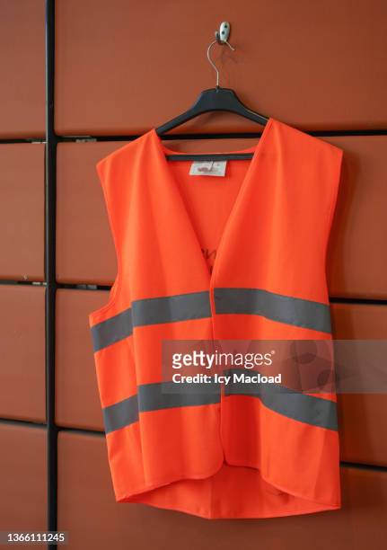 orange vest with fluorescent gray stripes hanging on an orange wall - reflective clothing stock-fotos und bilder