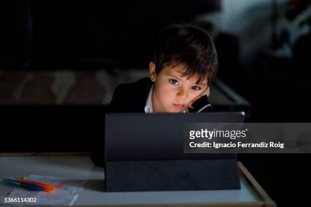 handsome boy in school uniform does homework at home with a tablet - tecnología foto e immagini stock