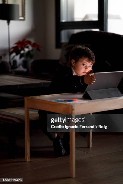 handsome boy in school uniform teaching online class at home with a tablet. - tecnología foto e immagini stock