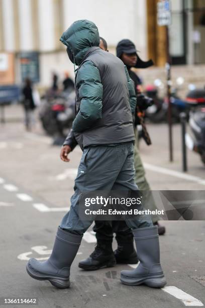 Guest wears a green gray hoodie puffer jacket, a gray sleeveless puffer jacket, gray cargo pants, gray plastic rain ankle boots, outside Rains ,...