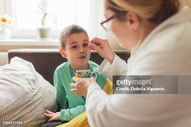 woman feeding her sick young son - food allergy stock pictures, royalty-free photos & images