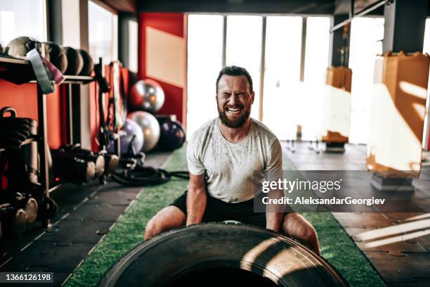 male athlete wincing with effort during truck tire gym workout - svett bildbanksfoton och bilder