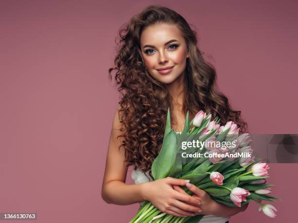 young beautiful woman holding a bouquet of flowers - holding flowers stock pictures, royalty-free photos & images