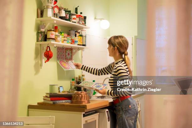 woman sticking adhesive tiles to freshly coated kitchen wall for decoration - women pastel stock pictures, royalty-free photos & images