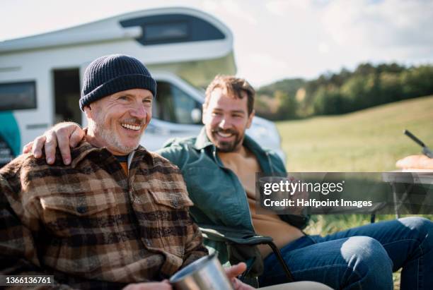 senior father with his adult son camping together with caravan in nature. - family camping stock-fotos und bilder