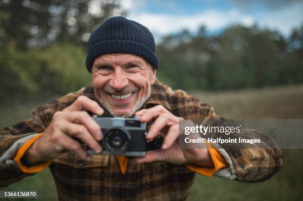 close-up of senior man with camera outdoors in forest in autumn day. - old photographer imagens e fotografias de stock