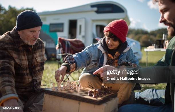 little boy camping with his father and grandfather in nature, playing chess together. - family caravan stockfoto's en -beelden