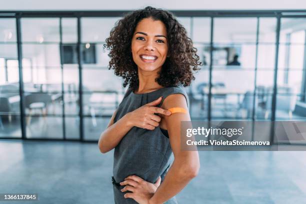 woman showing her shoulder after getting vaccinated. - vaccine bandage stock pictures, royalty-free photos & images