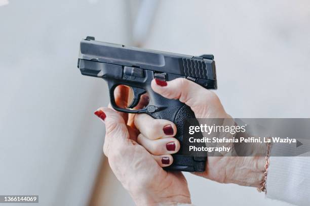 senior woman's hand holding a pistol - firing handgun stock pictures, royalty-free photos & images