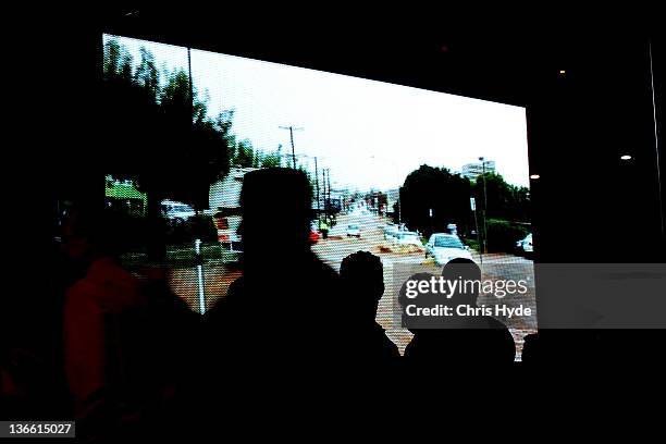 Toowoomba residents watch footage of the floods during a memorial service to unveil The Stone of Hope on January 9, 2012 in Toowoomba. January marks...