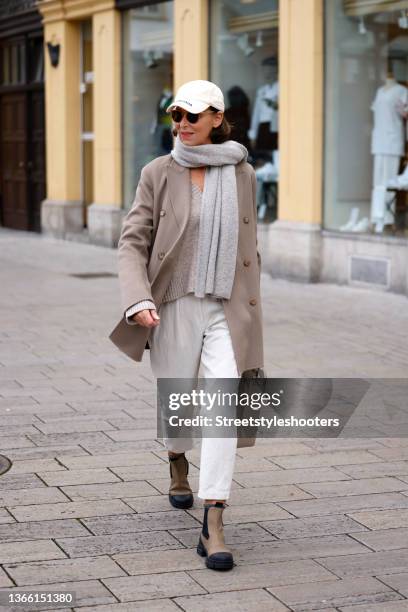 Fashion designer Eva Lutz wearing a grey scarf by Joseph, a beige pullover by Iro, a beige jacket by Joseph, a cream colored cap by Balenciaga, a...