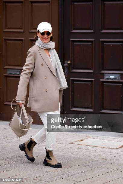 Fashion designer Eva Lutz wearing a grey scarf by Joseph, a beige pullover by Iro, a beige jacket by Joseph, a cream colored cap by Balenciaga, a...