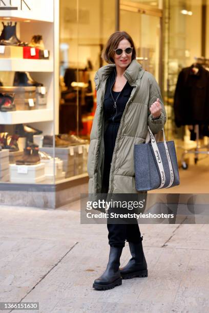 Fashion designer Eva Lutz wearing a long olive green coat by Zara, a black overall by Jonathan Simkai, black boots by Paloma Barcelo and a blue-grey...