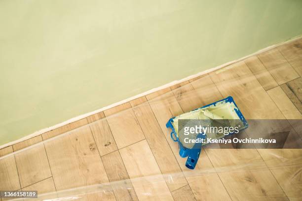 paint roller in paint tray with white color in the tray on brown paper on wooden floor - paint tray stock-fotos und bilder