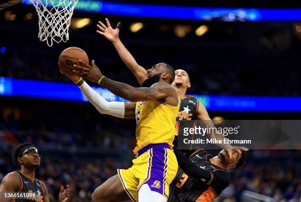 LeBron James of the Los Angeles Lakers drives over Chuma Okeke and `x4 during a game at Amway Center on January 21, 2022 in Orlando, Florida. NOTE TO...