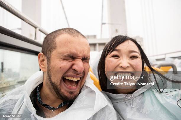 a couple enjoys sightseeing on an open-top bus despite the rain - rain couple stockfoto's en -beelden