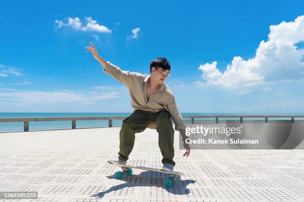 asian men  skateboarding outdoors on beautiful summer day - free skate - fotografias e filmes do acervo