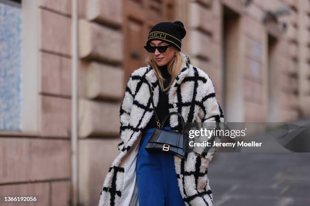 Sonia Lyson wearing Prada black loafer, Reformation black and white coat, Urban Outfitters blue joggingpants, Anine Bing black shades and Zara black...