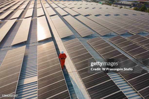 assistance technical worker in uniform is checking an operation and efficiency performance of photovoltaic solar panels. unidentified solar power engineer touches solar panels with his hand at sunset. - field service stock pictures, royalty-free photos & images