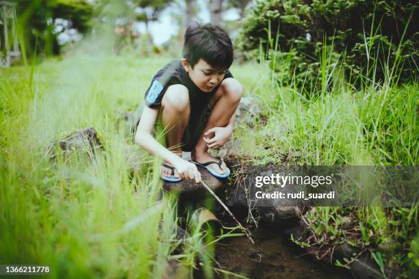 asiatisches kind, das alleine am graben am hof spielt - children playing in yard stock-fotos und bilder