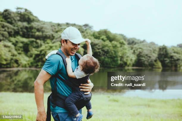 padre jugando y cargando a su bebé en el bosque - portabebés fotografías e imágenes de stock