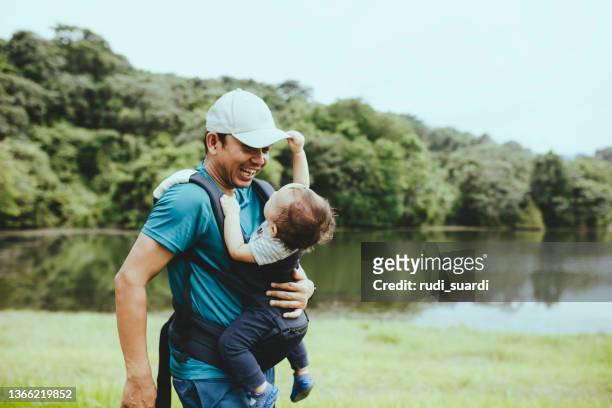father  playing and carrying his baby in the forest - indonesia family stock pictures, royalty-free photos & images