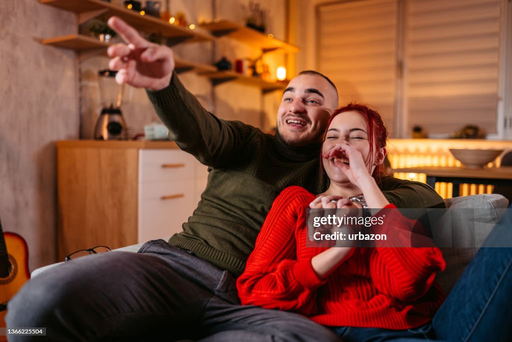 ソファでテレビを見ている若いカップル