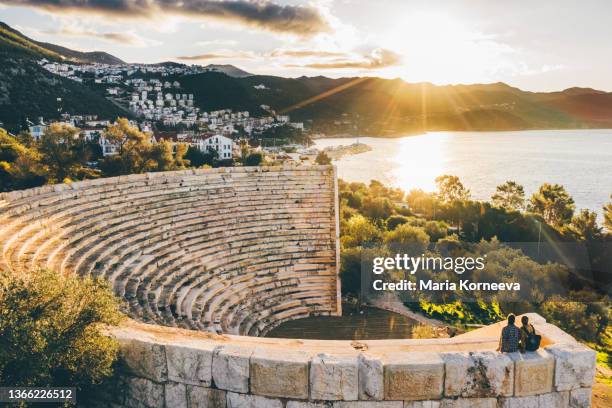 tourist couple sitting on highest stone step of old amphitheater . - helicopter view stock pictures, royalty-free photos & images