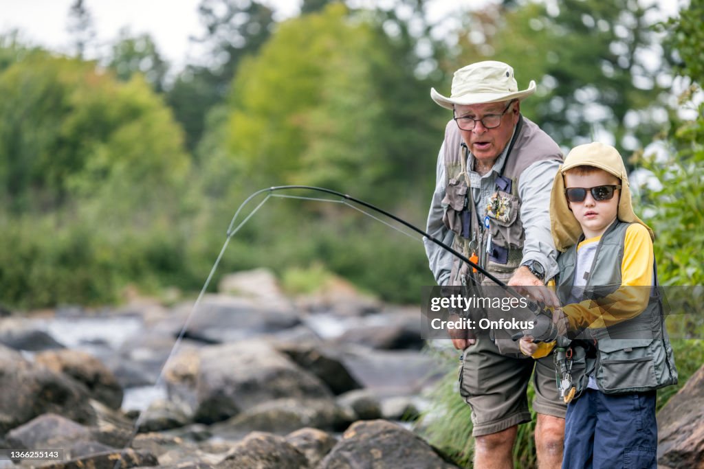 Cute Redhead Boy and Grandfather Fishing in the River in Quebec