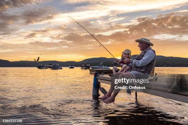 grand-père et petit-fils pêchant au coucher du soleil en été, québec, canada - freshwater fishing stock photos et images de collection