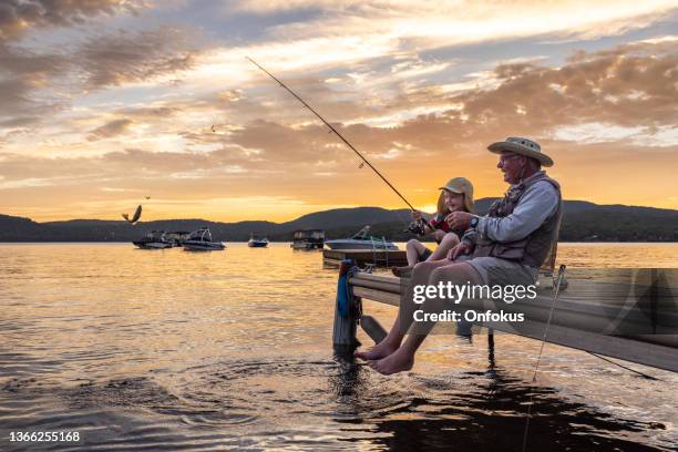 grandfather and grandson fishing at sunset in summer, quebec, canada - zoetwater hengelen stockfoto's en -beelden