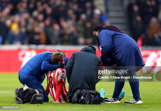 Mathias Jensen of Brentford receives medical attention during the Premier League match between Brentford and Wolverhampton Wanderers at Brentford...