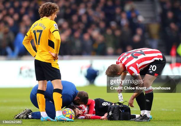 Mathias Jensen of Brentford receives medical attention during the Premier League match between Brentford and Wolverhampton Wanderers at Brentford...