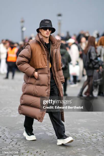 Guest wears a black laces bob from Jacquemus, black sunglasses, a black t-shirt, a silver chain pendant necklace, a black ribbed velvet shirt, a...