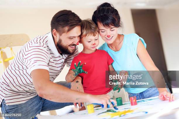 young parents play together with their cute son, paint with colorful paints and have fun - baby paint hand stock-fotos und bilder