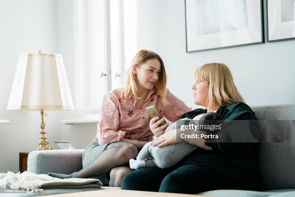 Lesbian couple with their baby boy using mobile phone at home