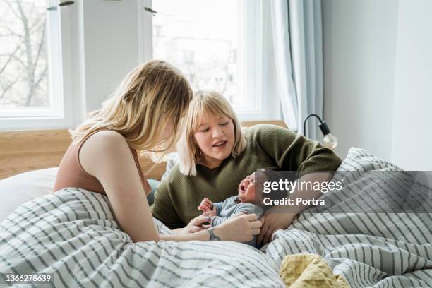 women couple in bed with crying baby boy - moms crying in bed stock pictures, royalty-free photos & images