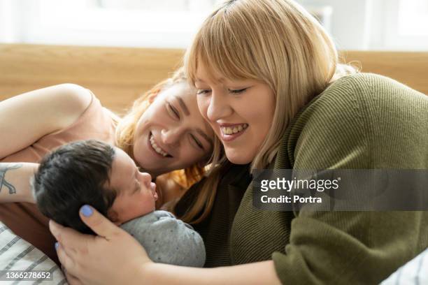 lesbians looking at their baby boy on bed - cute lesbian couples 個照片及圖片檔
